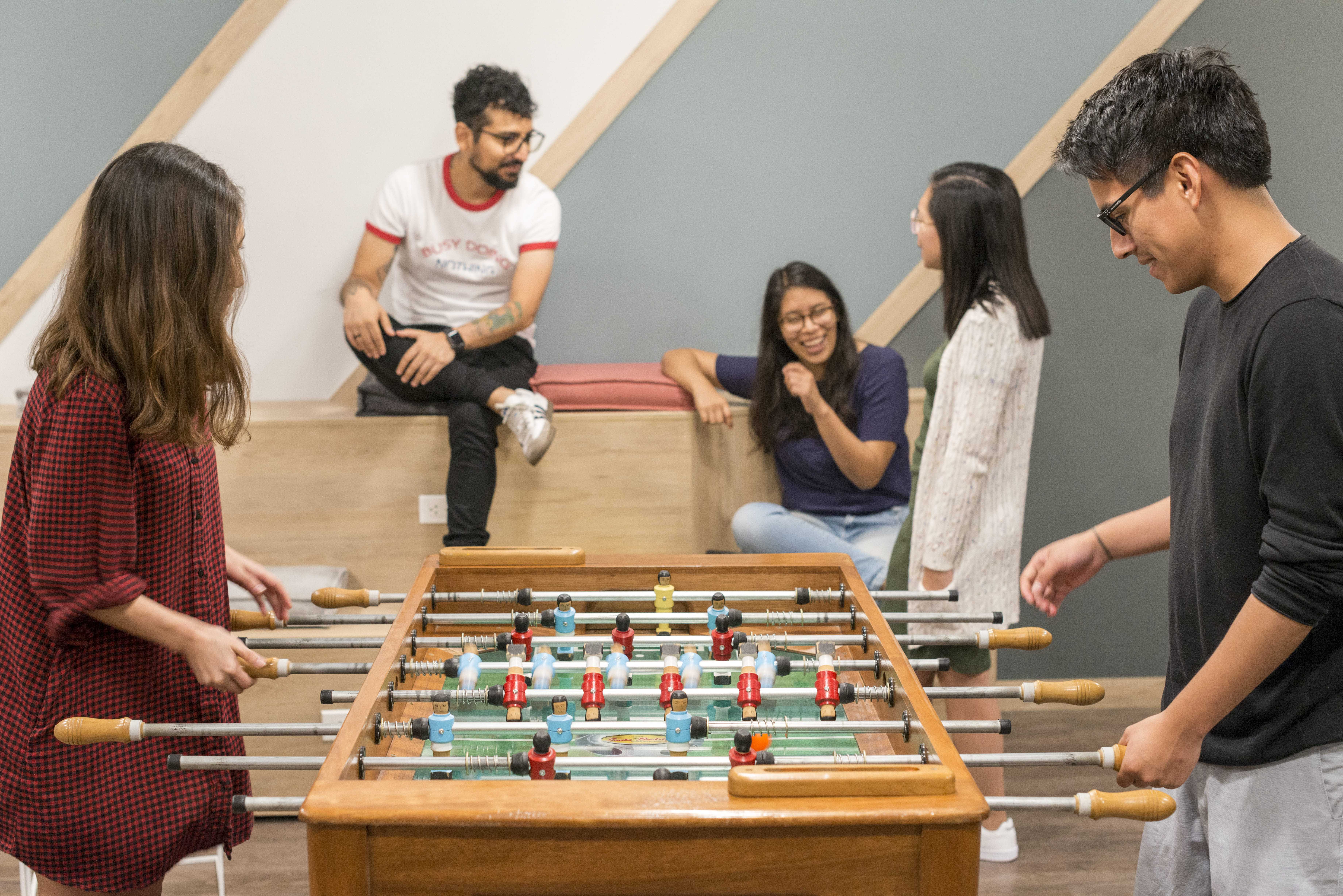 jovenes jugando futbolito de mesa en una sala de juegos de comunal
